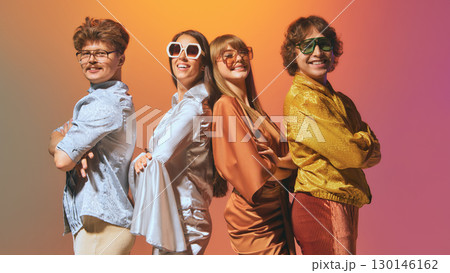 Friends standing back to back in vintage fashion outfits smiling 130146162