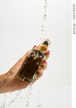 Hand holding cosmetic spray bottle with water splash on white background Hand holding cosmetic spray bottle with water splash on white background 130146203