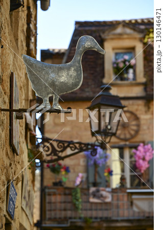 Charming streets of Sarlat-La-Caneda featuring a metal duck sign and beautifully decorated buildings 130146471