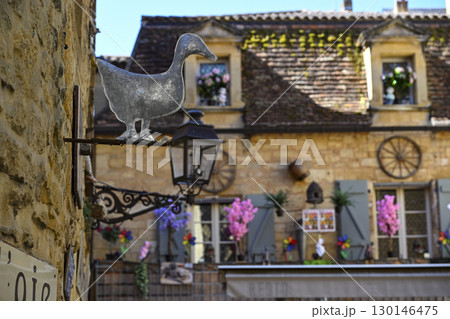 Charming streets of Sarlat-La-Caneda featuring a metal duck sign and beautifully decorated buildings 130146475