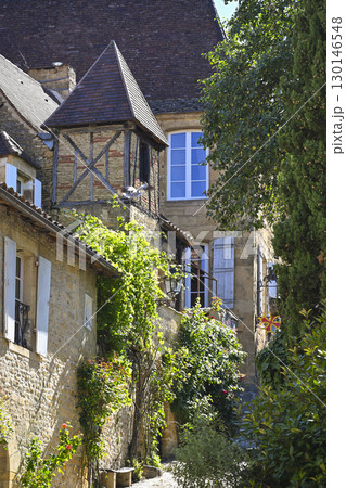 Charming street in Sarlat, Dordogne, featuring traditional architecture and lush greenery along Rue 130146548
