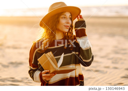 Romantic woman reading book sit on plaid have picnic outdoors on sea sand beach background Romantic woman reading book sit on plaid have picnic outdoors on sea sand beach background 130146943