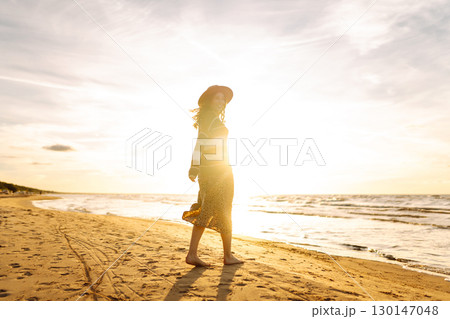 Carefree woman relaxing on coast at sunset. Windy autumn days. The concept of relaxation Carefree woman relaxing on coast at sunset. Windy autumn days. The concept of relaxation 130147048