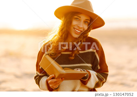 Romantic woman reading book sit on plaid have picnic outdoors on sea sand beach background Romantic woman reading book sit on plaid have picnic outdoors on sea sand beach background 130147052