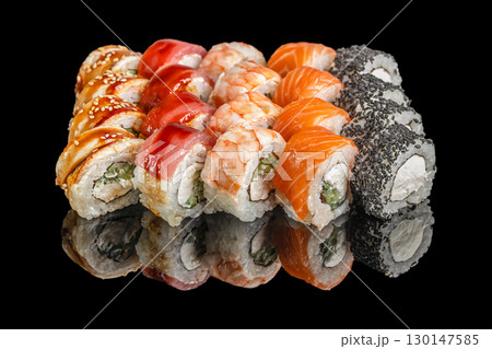 Assorted sushi rolls with salmon, tuna, shrimp, and sesame on black background 130147585