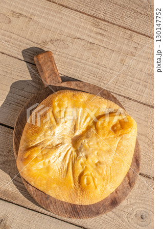Whole smoked cheese on rustic wooden board. Top view. Copy space 130147752