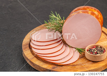 Sliced smoked sausage with pepper and rosemary on wooden board. top view. copy space 130147755