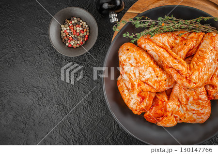 Raw marinated turkey wings with spices and herbs on black plate. top view. copy space 130147766