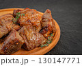 Close-up of grilled pork shashlik pieces on wooden plate with herbs 130147771