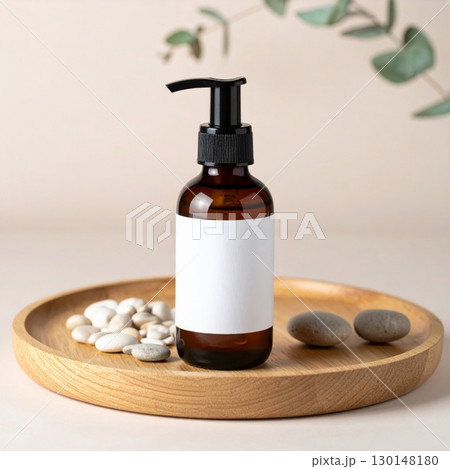 Amber Glass Bottle with White Label on Wooden Tray with Stones and Greenery 130148180