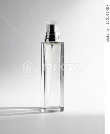 Elegant Clear Glass Perfume Bottle with Silver Sprayer on a White Surface Elegant Clear Glass Perfume Bottle with Silver Sprayer on a White Surface 130148407