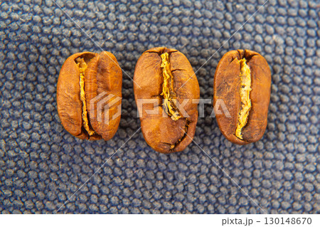 Close-up of roasted coffee beans scattered on a dark textured background 130148670
