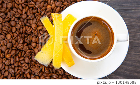 Rich espresso in a white cup paired with cheese sticks, nestled among coffee beans  130148688