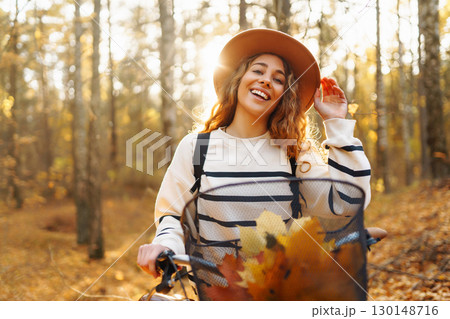 Smilling woman with bicycle enjoying autumn weather in park. Woman walking in autumn forest. Smilling woman with bicycle enjoying autumn weather in park. Woman walking in autumn forest. 130148716