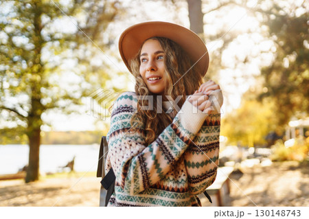 Sunny lifestyle portrait of young stylish woman walking on park, wearing cute trendy hat. Relaxation Sunny lifestyle portrait of young stylish woman walking on park, wearing cute trendy hat. Relaxation 130148743