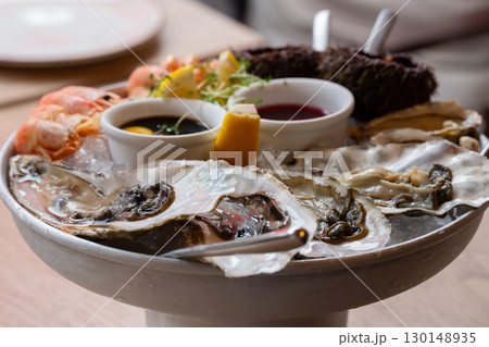 Seafood (oysters, shrimps, sea-urchins, mussels) are decoratively put on ice in a big plate 130148935