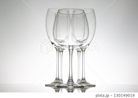 Elegant wine glasses with long stems and clear bowls, arranged in a line with reflections Elegant wine glasses with long stems and clear bowls, arranged in a line with reflections 130149019