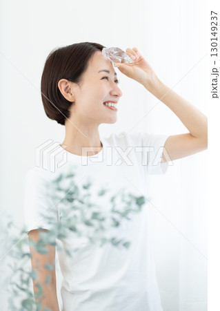 氷で肌を冷やす透明感のある女性 笑顔 上半身 130149237
