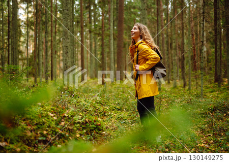 Female tourist with backpack in forest walks, enjoys nature of forest. Concept of nature, relaxation 130149275