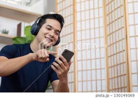 Young man enjoying music and smartphone in modern home setting 130149369