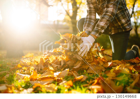 Man cleans the autumn park from yellow leaves. Cleaning, and ecology concept. Seasonal gardening. 130149668