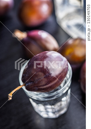 Plums and distilled alcohol on black table. Plum brandy shot. Plums and distilled alcohol on black table. Plum brandy shot. 130149703