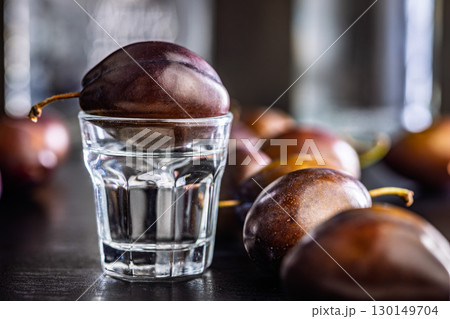 Plums and distilled alcohol on black table. Plum brandy shot. Plums and distilled alcohol on black table. Plum brandy shot. 130149704