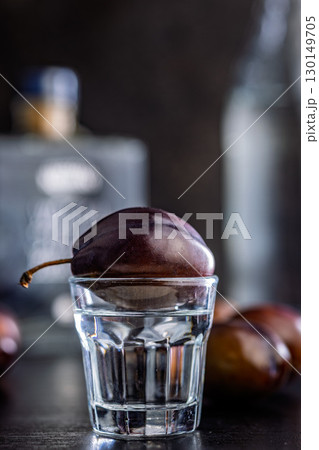 Plums and distilled alcohol on black table. Plum brandy shot. 130149705