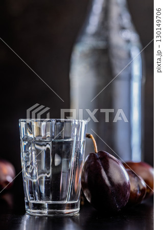 Plums and distilled alcohol on black table. Plum brandy shot. Plums and distilled alcohol on black table. Plum brandy shot. 130149706