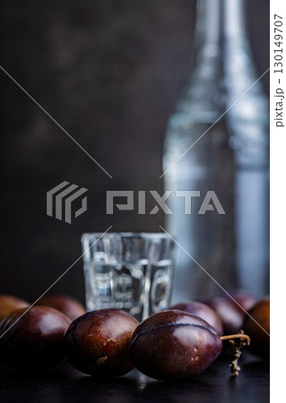 Plums and distilled alcohol on black table. Plum brandy shot. Plums and distilled alcohol on black table. Plum brandy shot. 130149707