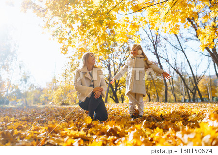 Young Mother and daughter walking in the park and enjoying the beautiful autumn nature. Walk, family Young Mother and daughter walking in the park and enjoying the beautiful autumn nature. Walk, family 130150674