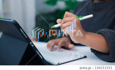 Person analyzing financial growth and stock market data on digital tablet with stylus and holographic candlestick chart for modern investment and business strategy concept 130151553