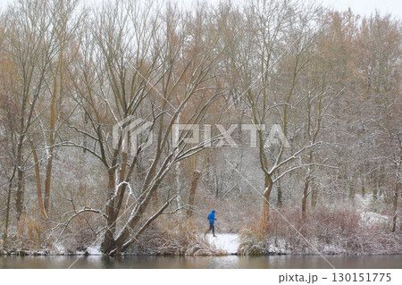 People Walking Through Snowy Forest by Lake 130151775