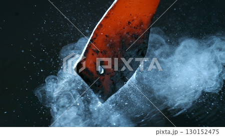 Blacksmith puts the red-hot forged metal part into cold water , close-up 130152475