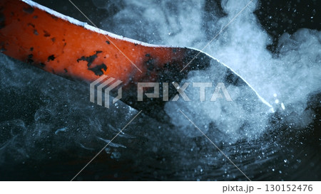 Blacksmith puts the red-hot forged metal part into cold water , close-up 130152476