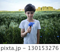 Beautiful boy in flowers. Handsome teenager in nature with flowers in her hands. 130153276