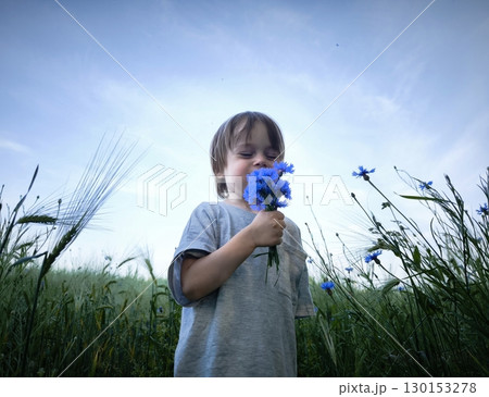 Beautiful little boy in flowers. A cute child in nature with flowers in her hands 130153278