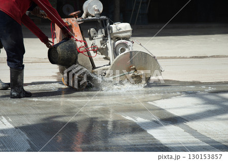 Workers are using a concrete road cutter. 130153857