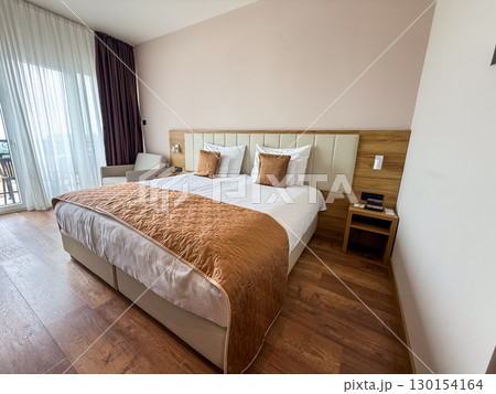 Bed in a hotel room. Comfort, relaxation, hospitality and travel accommodation interior. Bed in a hotel room. Comfort, relaxation, hospitality and travel accommodation interior. 130154164