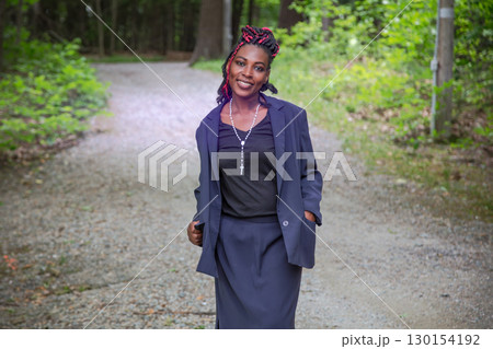 Professional African businesswoman walking on forest trail during work break Professional African businesswoman walking on forest trail during work break 130154192