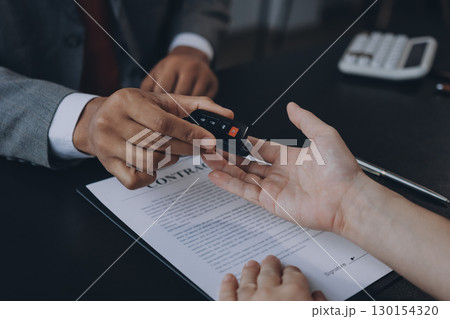Car salesman gave the keys to the customers who signed the purchase contract legally, Successful completion of car sales, Purchase contract and key delivery. 130154320