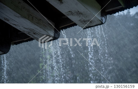 Heavy rainstorm falling from dark wooden roof eaves with vertical streaks of water Heavy rainstorm falling from dark wooden roof eaves with vertical streaks of water 130156159