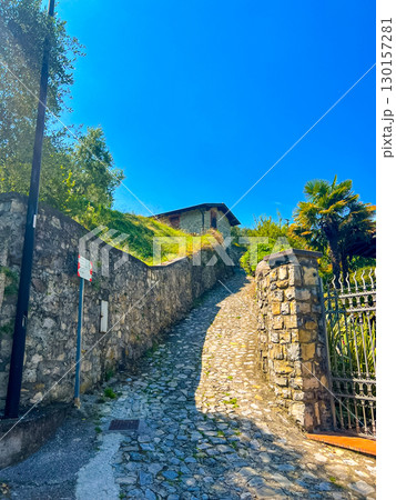 Picturesque stone road leading along a historic fence in carzano, italy Picturesque stone road leading along a historic fence in carzano, italy 130157281