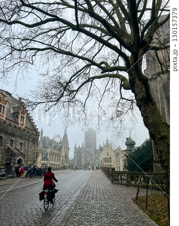 Cyclist Riding Through Historic Cobblestone Street in Charming Ghent, Belgium Cyclist Riding Through Historic Cobblestone Street in Charming Ghent, Belgium 130157379