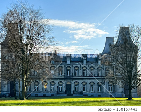 Historic mansion surrounded by lush green lawn and trees under a clear blue sky Historic mansion surrounded by lush green lawn and trees under a clear blue sky 130157443