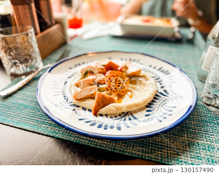 Plate of chicken served with puree and garnish on decorative dish. Cuisine, hospitality, and dining presentation concept for guest experience and leisure. 130157490