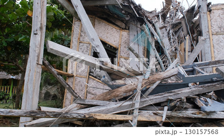 Close-up of destroyed bamboo hut on tropical coast showing storm aftermath  130157568