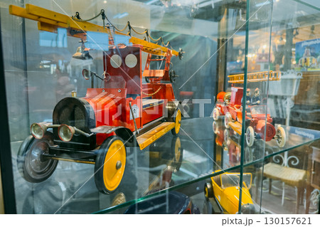 Display case featuring vintage red toy fire trucks with ladders and classic detailing. Vintage toys, nostalgic memorabilia, childhood relics, antique toy market 130157621