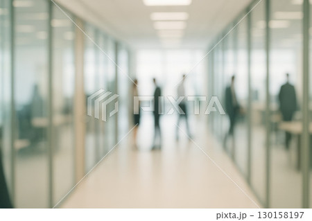 Blurred office corridor with glass partitions and people standing, soft focus creating calm professional atmosphere in modern business environment 130158197