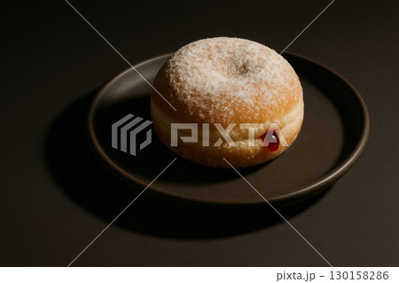 Powdered sugar donut with jelly filling on dark plate minimal food photography with dramatic shadow lighting, sweet dessert with soft texture and rich flavor Powdered sugar donut with jelly filling on dark plate minimal food photography with dramatic shadow lighting, sweet dessert with soft texture and rich flavor 130158286